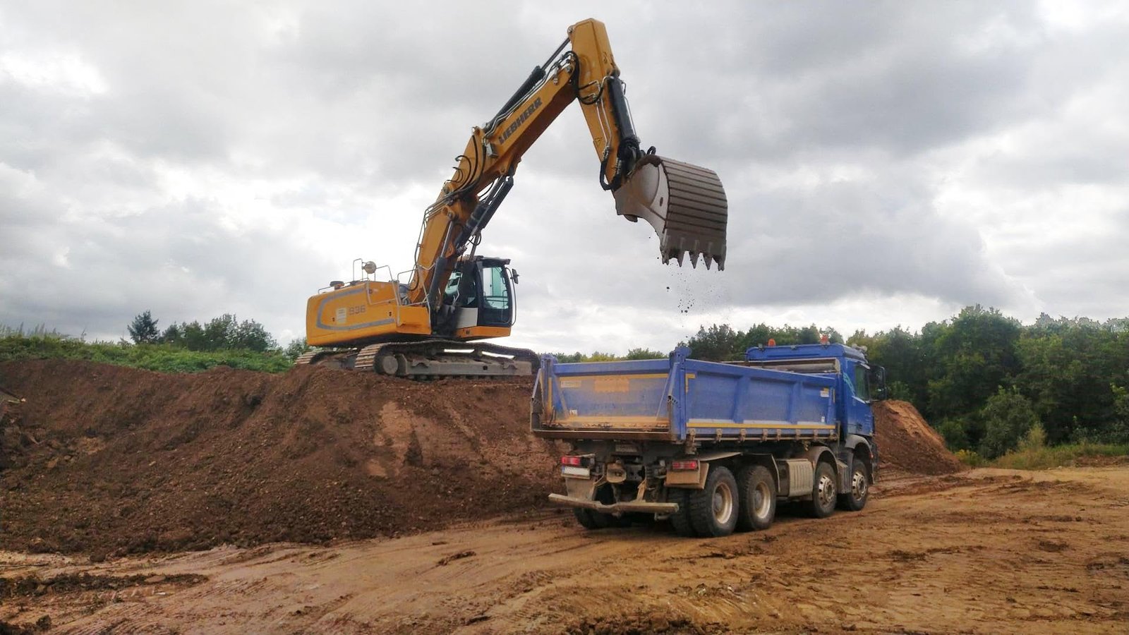 Bagger belädt LKW auf einer Baustelle